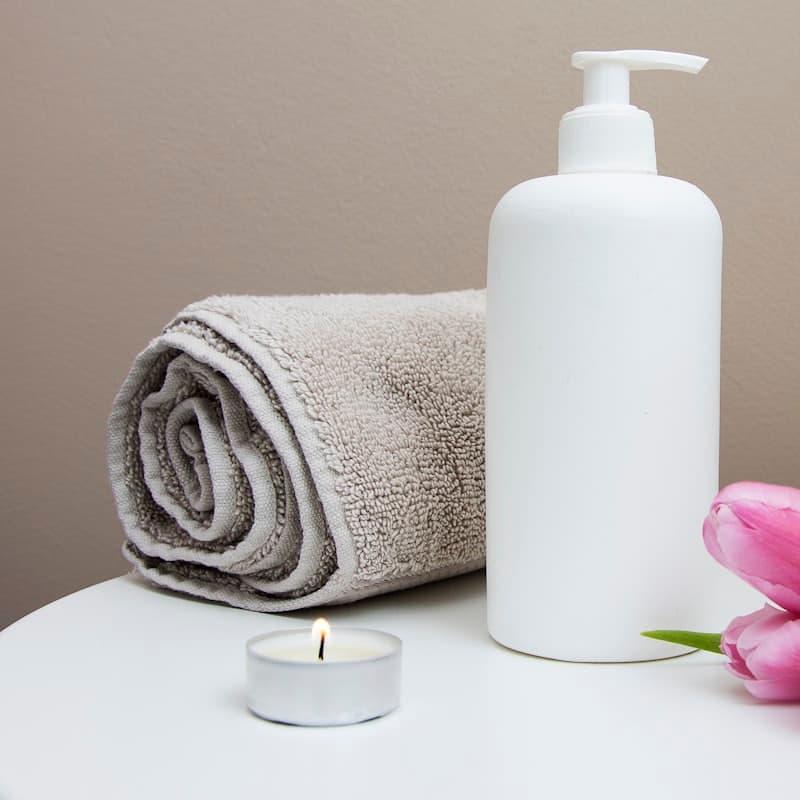 Folded towels, oil, and a lit candle